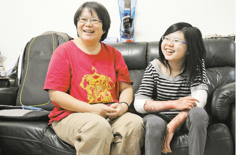 白加士街違規唐樓火警倖存者鄧岢娭（右），全身嚴重燒傷，雙腳肌肉大量壞死，瘦得剩下骨頭，長短腳更令她舉步維艱。但岢娭與母親（左）生性樂觀，每天在歡笑聲中重過新生。她們呼籲全港市民，不要再忍受身邊的樓宇違規，必須迫使政府執法改善，「不要怕事，一定要出聲，那關乎你條命！」（明報記者攝）