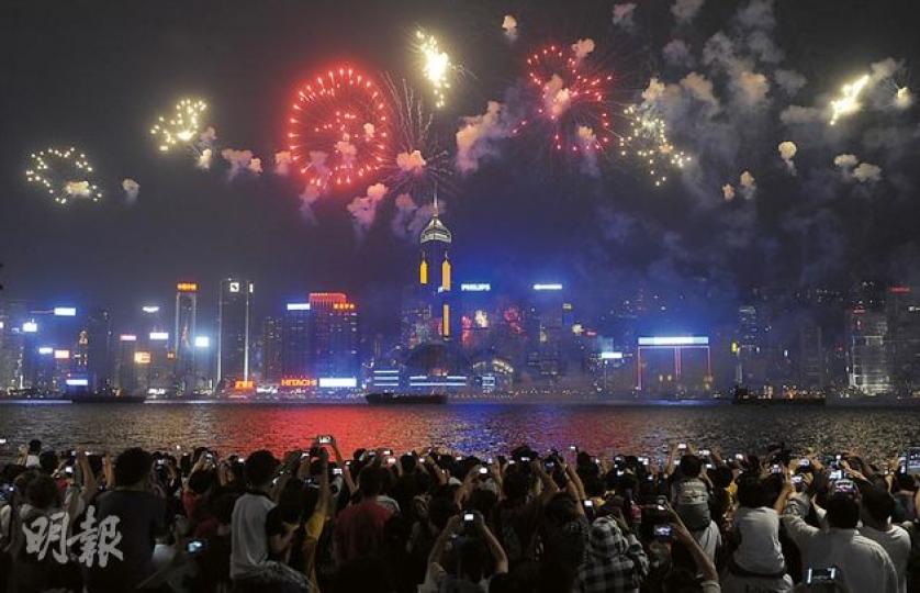 維港昨晚舉行國慶63周年煙花匯演，維港兩岸大批市民和旅客夾道觀賞。今年煙花背景音樂包括紅歌《紅旗頌》等，天空則發放「中国」簡體字樣煙花（圖），不少市民讚歎煙花燦爛。（余俊亮攝）黃先生（右二）昨與家人觀賞煙花，他認為毋須將政治爭拗帶入煙花匯演。（余俊亮攝）