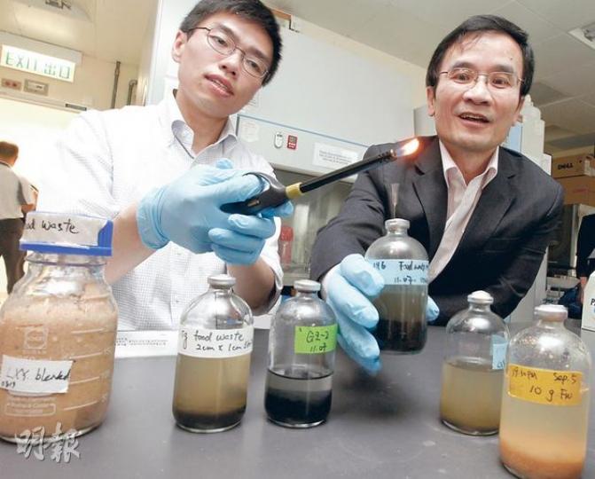 城大實驗人員將廚餘放入儲有細菌群組的器皿內，成功分解出甲烷。主責研究的教授李鈞瀚（左）指用火點燃可見到藍色火焰，證明燃料純淨較少雜質。右為城大能源及環境學院院長陳仲良。（李紹昌攝）