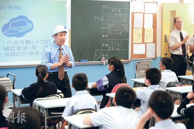 六年級國教首課教「帽子思考法」,用不同顏色的帽代表正反兩面、客觀和情感等,讓學生從不同角度分析國慶及海難的升旗儀式。圖為執教的老師施志勁(圖中)示範,戴上白帽就要從客觀的角度分析,右一為校長梁紀昌。(尹錦恩攝)(明報製圖) 六年級國教首課教「帽子思考法」,用不同顏色的帽代表正反兩面、客觀和情感等,讓學生從不同角度分析國慶及海難的升旗儀式。圖為執教的老師施志勁(圖中)示範,戴上白帽就要從客觀的角度分析,右一為校長梁紀昌。(尹錦恩攝)(明報製圖)