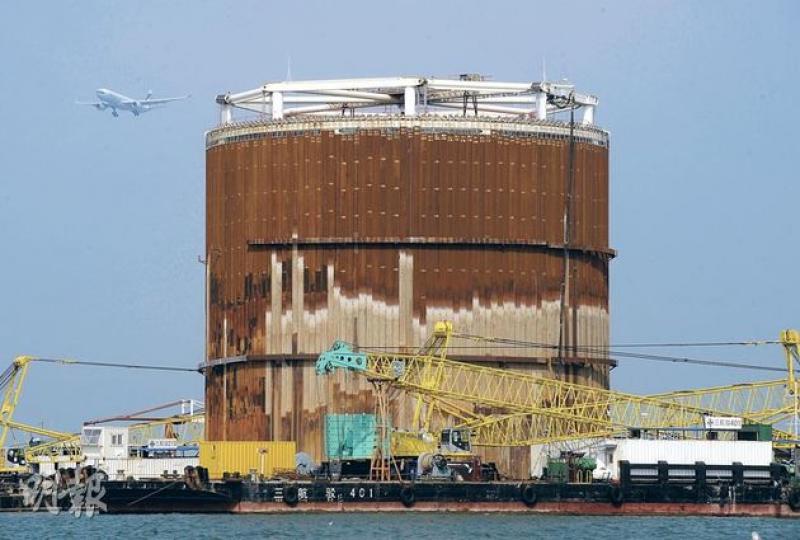 政府在東涌填海建人工島以配合港珠澳大橋工程,首次引用31米直徑的「大鋼筒」以沉箱方式在海上築堤,未料其中一鋼筒(圖)內的工作台急墜,釀成工作台上工人1死14傷。(余俊亮攝)從現場附近海面另一個建造中的大鋼筒的骨架可見,筒內8條支柱頂部都有滑輪,原可控制臨時升降台上升下降,但有工會引述受傷工人稱,肇事大鋼筒滑輪疑故障,令工作台傾側急墜引發意外。(余俊亮攝) 政府在東涌填海建人工島以配合港珠澳大橋工程,首次引用31米直徑的「大鋼筒」以沉箱方式在海上築堤,未料其中一鋼筒(圖)內的工作台急墜,釀成工作台上工人1死14傷。(余俊亮攝)從現場附近海面另一個建造中的大鋼筒的骨架可見,筒內8條支柱頂部都有滑輪,原可控制臨時升降台上升下降,但有工會引述受傷工人稱,肇事大鋼筒滑輪疑故障,令工作台傾側急墜引發意外。(余俊亮攝)