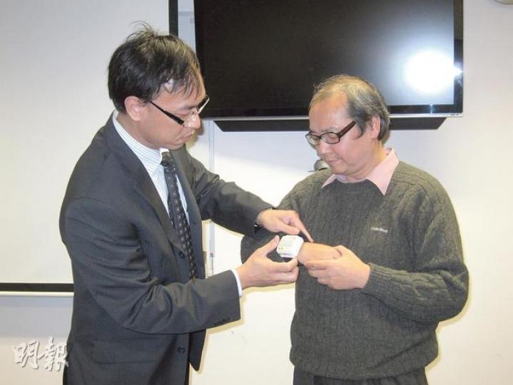 理大復康治療科學系副教授方乃權(左)為新健社主席劉劍雄(右)戴上的,就是「感知提示手表」。(勞雅文攝) 理大復康治療科學系副教授方乃權(左)為新健社主席劉劍雄(右)戴上的,就是「感知提示手表」。(勞雅文攝)