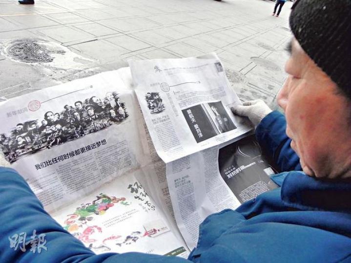 在北京街頭,有讀者閱讀最新一期《南方周末》的「新年獻詞」。(明報記者攝)(明報製圖) 在北京街頭,有讀者閱讀最新一期《南方周末》的「新年獻詞」。(明報記者攝)(明報製圖)