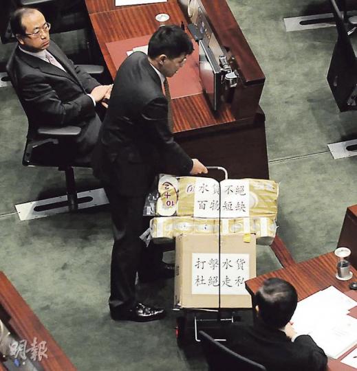 新民主同盟范國威突然「水貨客上身」,推住裝滿奶粉嘅手推車行近梁振英,希望向佢反映水貨客肆虐北區嘅問題。 (余俊亮攝) 新民主同盟范國威突然「水貨客上身」,推住裝滿奶粉嘅手推車行近梁振英,希望向佢反映水貨客肆虐北區嘅問題。 (余俊亮攝)