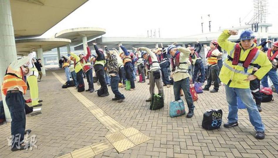 因發生工作台傾側奪命工業意外而停工兩個多月的「港珠澳人工島填海大鋼筒工程」昨復工,為確保復工安全,60多名工人昨乘船上班前先於東涌碼頭穿起整齊安全裝備包括頭盔、反光衣、救生衣和安全鞋等,再做熱身操,工頭特別提醒工人要注意安全。(盧翊銘攝)記者昨晨乘船到港珠澳橋人工島填海大鋼筒的躉船附近近距離觀察,只見部分工人坐在躉船上釣魚,未如想像中忙碌;填海大鋼筒內的工作台原應由兩邊躉船各以鋼纜繫緊固定,但昨日只見有一艘躉船和一組鋼纜,控制大鋼筒內工作台升降的8組滑輪也不見運作。(盧翊銘攝) 因發生工作台傾側奪命工業意外而停工兩個多月的「港珠澳人工島填海大鋼筒工程」昨復工,為確保復工安全,60多名工人昨乘船上班前先於東涌碼頭穿起整齊安全裝備包括頭盔、反光衣、救生衣和安全鞋等,再做熱身操,工頭特別提醒工人要注意安全。(盧翊銘攝)記者昨晨乘船到港珠澳橋人工島填海大鋼筒的躉船附近近距離觀察,只見部分工人坐在躉船上釣魚,未如想像中忙碌;填海大鋼筒內的工作台原應由兩邊躉船各以鋼纜繫緊固定,但昨日只見有一艘躉船和一組鋼纜,控制大鋼筒內工作台升降的8組滑輪也不見運作。(盧翊銘攝)