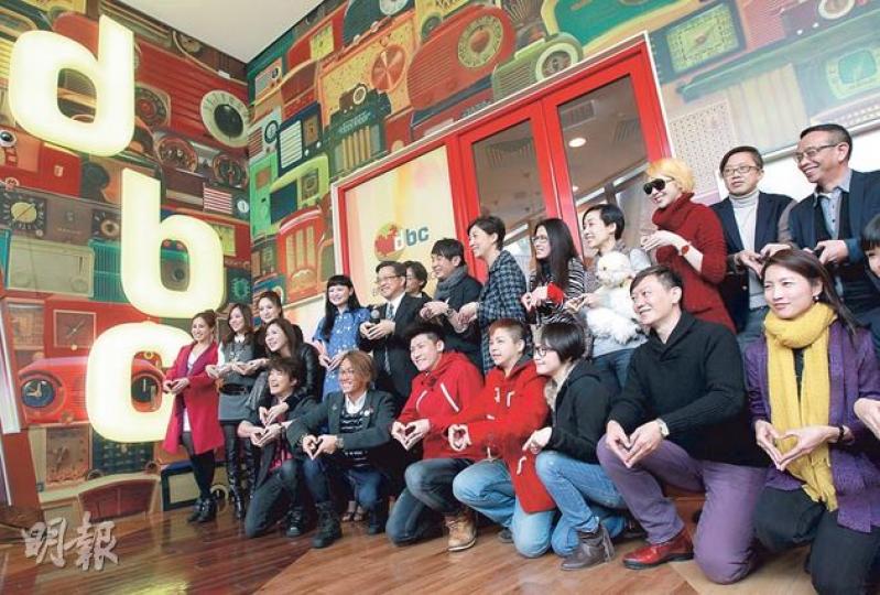 停播3個月的香港數碼電台（DBC）昨日復播，台長麥潤壽帶領10多名節目主持人在數碼港的總部內舉行復播亮燈儀式，眾人用雙手擺出心形圖案，叫出口號——「一個有心嘅電台」。（李澤彤攝）（明報製圖）