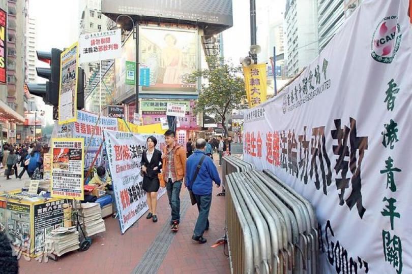 反法輪功嘅香港青年關愛協會,喺銅鑼灣掛出白色巨型橫額(右)。若從馬路望埋去,啱啱遮住法輪功嘅黃色「展板」,不過協會副會長林國安就唔肯講係咪「特登」咁做。 (李澤彤攝) 反法輪功嘅香港青年關愛協會,喺銅鑼灣掛出白色巨型橫額(右)。若從馬路望埋去,啱啱遮住法輪功嘅黃色「展板」,不過協會副會長林國安就唔肯講係咪「特登」咁做。 (李澤彤攝)