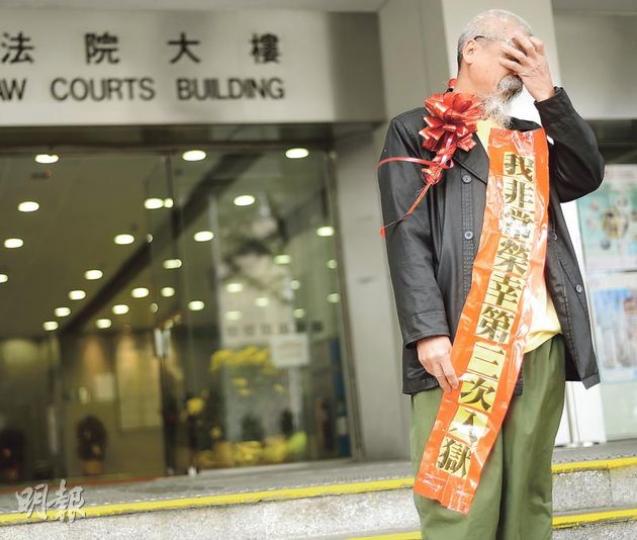 身為家庭支柱的古思堯因展示塗污國旗及區旗等被判囚9個月，其妻子及13歲兒子現於河南省。裁判官責備他對家人不負責任，古回應說﹕「大是大非比家庭重要。」他昨在法院外戴上寫有「我非常榮幸第三次入獄」的綵帶。（余俊亮攝）古思堯昨坐囚車離開法庭時，高舉被鎖上手銬的雙手大叫﹕「李旺陽，你永垂不朽」，同車懲教人員即時阻止。（余俊亮攝）