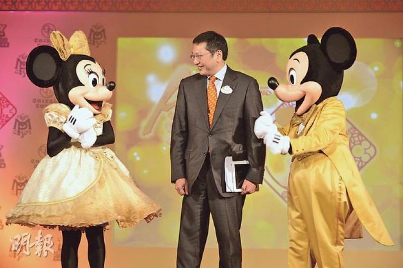 香港迪士尼樂園昨日公布業績,行政總裁金民豪(中)昨於發布會上緊隨穿上金裝的米奇及米妮老鼠等迪士尼角色表演歌舞後出場,並宣布該園首次轉虧為盈,錄得逾1億元純利。(盧翊銘攝) (明報製圖) 香港迪士尼樂園昨日公布業績,行政總裁金民豪(中)昨於發布會上緊隨穿上金裝的米奇及米妮老鼠等迪士尼角色表演歌舞後出場,並宣布該園首次轉虧為盈,錄得逾1億元純利。(盧翊銘攝) (明報製圖)