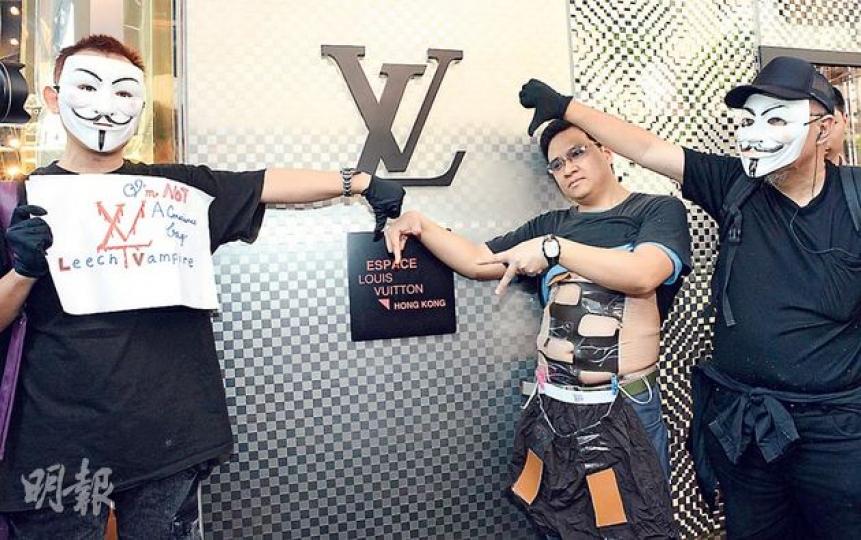 網民發起的「千人圍LV」行動,昨日活動開始時僅得3人現身,包括兩名戴上「V煞」面具的網民,及鄧簡文(中),身穿「格仔腹肌裝」以諷刺LV指使用格仔設計商戶侵權。(陳淑安攝) 網民發起的「千人圍LV」行動,昨日活動開始時僅得3人現身,包括兩名戴上「V煞」面具的網民,及鄧簡文(中),身穿「格仔腹肌裝」以諷刺LV指使用格仔設計商戶侵權。(陳淑安攝)