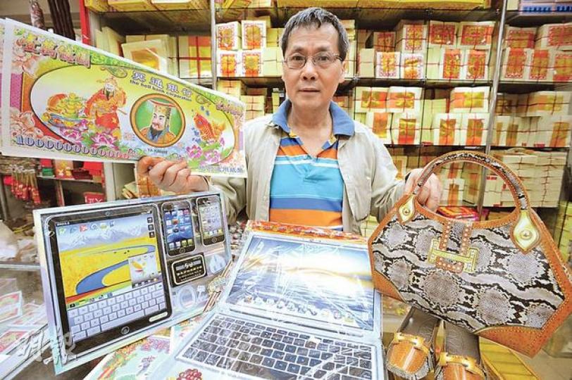 紙紮店俊城行負責人杜千送手中的冥鈔面額高達1萬億元，售價較其他面額貴約1倍，一疊20張售5元。他又稱，近日只敢出售普通款式的手袋（右），疑似名牌的全數收起。（尹錦恩攝）