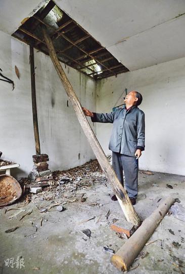 都江堰聚源鎮普星村92歲村民林世勳（圖）的村屋，5年前地震留下的大窟窿仍未修復，用石頭和兩條木樁加固支撐。（余俊亮攝）