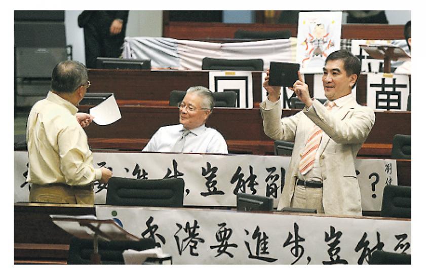 在等待投票完成表決710項修正案期間,自由黨鍾國斌(右)拿起平板電腦拍下議事廳場景,記錄「歷史一刻」。其他議員也乘機鬆一鬆。(余俊亮攝) 在等待投票完成表決710項修正案期間,自由黨鍾國斌(右)拿起平板電腦拍下議事廳場景,記錄「歷史一刻」。其他議員也乘機鬆一鬆。(余俊亮攝)