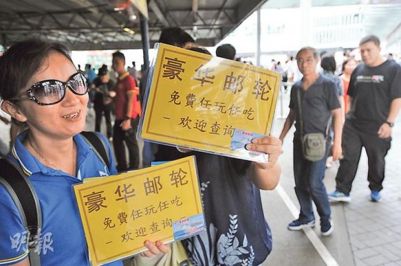 尖沙嘴天星碼頭外多名男女手持用簡體字寫着「豪華郵輪,免費任玩任吃」的宣傳牌,以招徠內地遊客。(尹錦恩攝) 尖沙嘴天星碼頭外多名男女手持用簡體字寫着「豪華郵輪,免費任玩任吃」的宣傳牌,以招徠內地遊客。(尹錦恩攝)