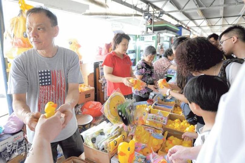 尖沙嘴碼頭報紙檔賣黃鴨精品，左邊兩人是檔主陳氏夫婦。橡皮巨鴨今晚將離開，昨日不少市民拍照巨鴨之餘，還向他們購買紀念品，生意大旺。 （葉家豪攝）只要讚好專頁，便可得到鴨仔紀念品。這個團購檔吸引不少人，開檔4天其專頁便超過2400人讚好，負責人表示他們旨在推廣。（姚文基攝）來自加拿大的Tiffany Crook（右）在港任職教師，與母親（左）一同看巨鴨，她認為香港人「瘋狂追鴨」是出於童年回憶，直言自己看到巨鴨心情也非常興奮。（姚文基攝）來自重慶的尹小姐（左）特地來香港看真正的巨鴨，她說，內地有很多「