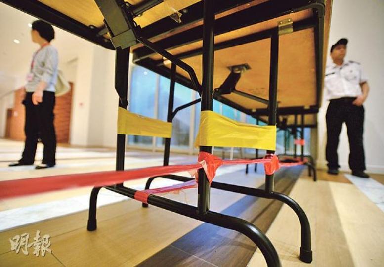 和平佔中嘅首個「防線」用齊膠紙、索帶同尼龍繩綁實枱腳，以防示威者衝擊，有人笑言似足電影《孤星淚》入面嘅路障。（盧翊銘攝）佔中義工陳玉峰（右）噚日負責應對傳媒，不停將最新消息以WhatsApp群組發放畀記者。（余俊亮攝）