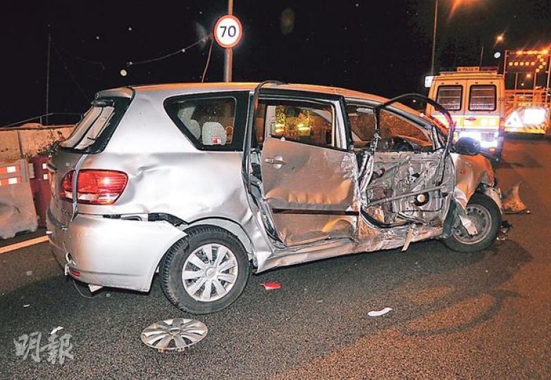 車禍中的七人車右邊車身嚴重凹陷，司機位車門外殼飛脫，零件外露。（蔡方山攝）公路旁20多個水馬被掃毁後碎片四散，而七人車司機位車門的外殼亦掉落地上，估計逾噸重的臨時燈柱石墩亦被撞至輕微移位。（蔡方山攝）