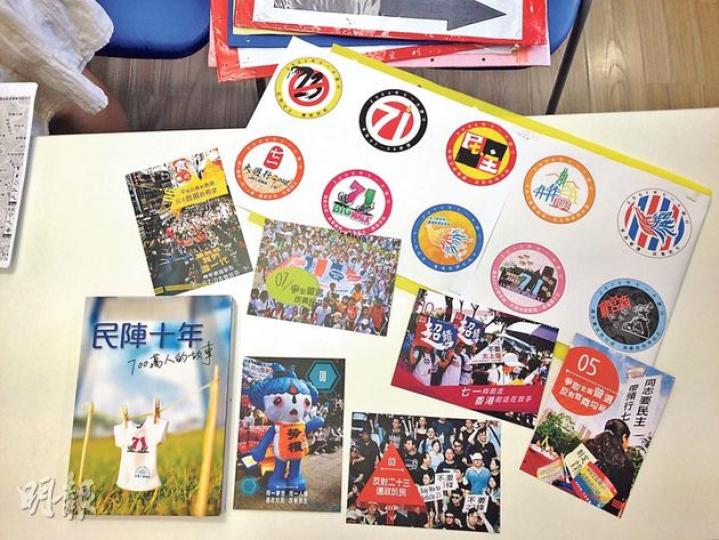 七一遊行10周年,民陣製作咗一系列紀念品記錄歷年遊行足迹,包括書(左下)、明信片(中)同襟章(右上),要買齊一套,盛惠100蚊。(何曉勤攝) 七一遊行10周年,民陣製作咗一系列紀念品記錄歷年遊行足迹,包括書(左下)、明信片(中)同襟章(右上),要買齊一套,盛惠100蚊。(何曉勤攝)