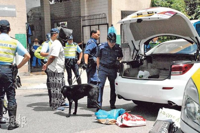 警方拔槍制服被截查時高速逃走的私家車司機（蒙頭者），並由警犬協助搜車，於車尾箱找出4套車牌，其中一套不屬於司機。（雲錦鋒攝）