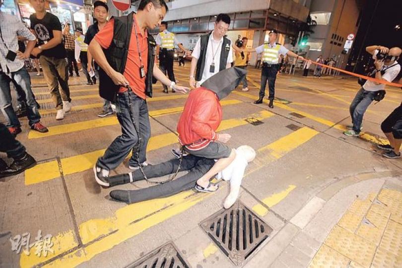 反黑組探員把其中一名疑犯押到北角書局街案發現場重組案情,疑犯騎在假人身上示範當日連環拳擊死者的過程。(衛永康攝) 反黑組探員把其中一名疑犯押到北角書局街案發現場重組案情,疑犯騎在假人身上示範當日連環拳擊死者的過程。(衛永康攝)