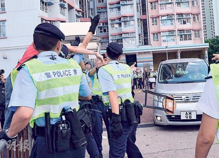 社民連副主席吳文遠(紅衣者)昨在梁振英離開時,手持摺櫈揮向對方座駕請願,諷刺曾說落區坐摺櫈聽民意的梁振英,其間多名警員上前阻止,摺櫈擲在地上,未有擊中梁的座駕(圖)。警方指他涉在公眾地方行為不檢,吳即場被鎖上手扣(圖2),由10多名警察帶上警車送元朗警署,他昨晚獲准以300元保釋,下月返署報到。(鄧宗弘攝) 社民連副主席吳文遠(紅衣者)昨在梁振英離開時,手持摺櫈揮向對方座駕請願,諷刺曾說落區坐摺櫈聽民意的梁振英,其間多名警員上前阻止,摺櫈擲在地上,未有擊中梁的座駕(圖)。警方指他涉在公眾地方行為不檢,吳即場被鎖上手扣(圖2),由10多名警察帶上警車送元朗警署,他昨晚獲准以300元保釋,下月返署報到。(鄧宗弘攝)