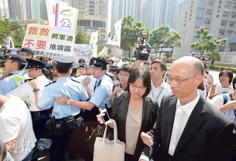 環境局長黃錦星(前排右一)昨到將軍澳出席西貢區議員安排的會議,與議員交流減廢藍圖。他到場時遇到場外一眾反對擴建將軍澳堆填區的政黨及市民示威,要由數十名警員築起人鏈保護入場。(盧翊銘攝) 環境局長黃錦星(前排右一)昨到將軍澳出席西貢區議員安排的會議,與議員交流減廢藍圖。他到場時遇到場外一眾反對擴建將軍澳堆填區的政黨及市民示威,要由數十名警員築起人鏈保護入場。(盧翊銘攝)