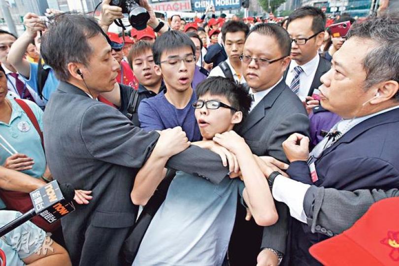 有自稱受民政署委託的保安人員,於學民思潮召集人黃之鋒(灰衣)接受訪問時,突然要求黃之鋒和黎汶洛(前排左二)離開,其後更將兩人強行拖走。混亂間黃之鋒被踩甩鞋。(李紹昌攝)學民思潮召集人黃之鋒(第二排左)和召集人黎汶洛(第二排右)昨到國慶升旗禮,做出代表「公民提名」的手勢,他們沒穿有標語的衣服,被要求離開前亦沒有叫口號。(李紹昌攝) 有自稱受民政署委託的保安人員,於學民思潮召集人黃之鋒(灰衣)接受訪問時,突然要求黃之鋒和黎汶洛(前排左二)離開,其後更將兩人強行拖走。混亂間黃之鋒被踩甩鞋。(李紹昌攝)學民思潮召集人黃之鋒(第二排左)和召集人黎汶洛(第二排右)昨到國慶升旗禮,做出代表「公民提名」的手勢,他們沒穿有標語的衣服,被要求離開前亦沒有叫口號。(李紹昌攝)