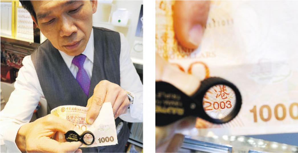 深水埗美麗華珠寶金行的總行營業部主任麥志偉,用放大鏡檢驗剛收來中銀2003年版千元鈔票,字樣清晰可見。(鍾炳然攝) 深水埗美麗華珠寶金行的總行營業部主任麥志偉,用放大鏡檢驗剛收來中銀2003年版千元鈔票,字樣清晰可見。(鍾炳然攝)