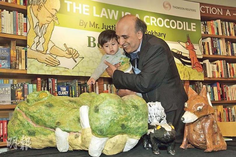 終審法院非常任法官包致金(右)手抱20月大男孫Zane(左)出席其新書《The Law is a Crocodile》的發布兼簽名會,其間他帶孫兒「滿場飛」,又讓孫兒欣賞由他親手用廢紙製作的書中主角公仔,包括鱷魚(左下起)、鼬鼠及狐狸,不過孫兒對「大場面」顯得有點害羞。(郭慶輝攝) 終審法院非常任法官包致金(右)手抱20月大男孫Zane(左)出席其新書《The Law is a Crocodile》的發布兼簽名會,其間他帶孫兒「滿場飛」,又讓孫兒欣賞由他親手用廢紙製作的書中主角公仔,包括鱷魚(左下起)、鼬鼠及狐狸,不過孫兒對「大場面」顯得有點害羞。(郭慶輝攝)