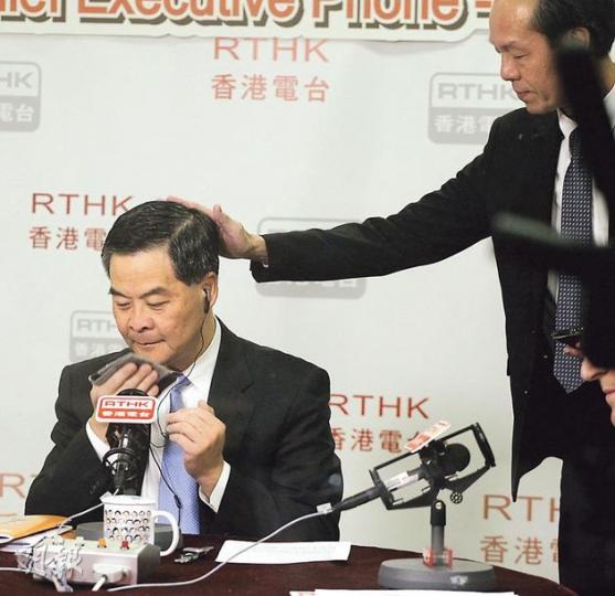 特首梁振英昨晨去港台第三台嘅施政報告英語特備節目,繼續為施政報告解畫。開咪之前,一名G4探員為佢掃一掃頭髮後尾枕,以免出鏡時頭髮彈起。(李紹昌攝) 特首梁振英昨晨去港台第三台嘅施政報告英語特備節目,繼續為施政報告解畫。開咪之前,一名G4探員為佢掃一掃頭髮後尾枕,以免出鏡時頭髮彈起。(李紹昌攝)