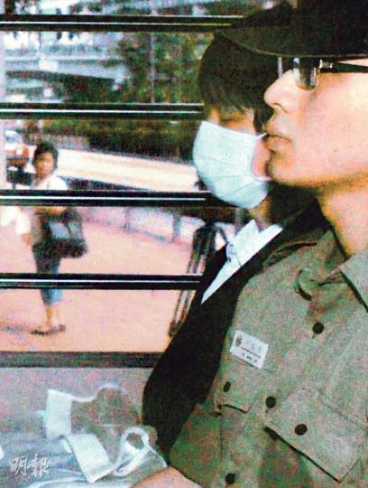 首被告周凱亮（戴口罩者）涉嫌殺死並肢解父母，昨乘囚車抵達高等法院。庭上播放周在警署落口供的錄影會面時，周神情淡定，表現冷靜，更跟隨片段的進度翻閱相關文件。（葉家豪攝）