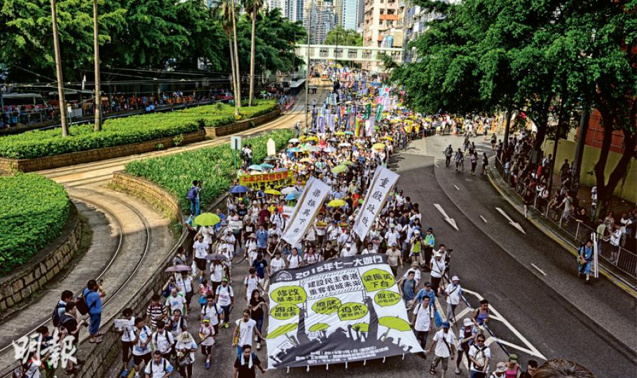 民陣昨在「後政改」的首場七一遊行，以「建設民主香港 重建我城未來」為主題，由學聯及教協帶頭，象徵透過老師和學生薪火相傳民主精神。遊行在下午約3時半起步，氣溫達32℃，在維園暴曬等待出發的人群明顯較少，站不滿兩個足球場，其後不少人在銅鑼灣加入。民陣公布昨有4.8萬人遊行，比去年民陣公布的51萬人遊行下跌逾九成，警方則公布高峰期有1.9萬人。（鄧宗弘攝）七一上街還是逛街？昨日在「後政改」的首場七一遊行，民陣公布有4.8萬人遊行，人數少於去年公布人數的十分之一。遊行人數雖暴跌，參加者撐起黃傘，吸引不少