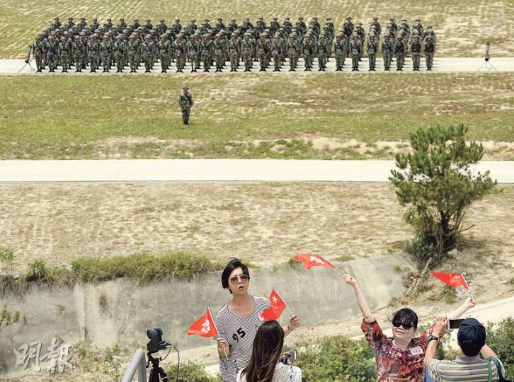 昨有逾500人獲邀觀看解放軍駐港部隊軍演,包括逾百名市民,未知屬何團體,他們觀看演練期間不時鼓掌,並興奮揮舞大會派發的區旗及國旗拍照。圖為歷時約45分鐘的軍演結束後,駐軍於中央平地列隊,有觀眾興奮揮動國旗與軍人「合照」。(余俊亮攝) 昨有逾500人獲邀觀看解放軍駐港部隊軍演,包括逾百名市民,未知屬何團體,他們觀看演練期間不時鼓掌,並興奮揮舞大會派發的區旗及國旗拍照。圖為歷時約45分鐘的軍演結束後,駐軍於中央平地列隊,有觀眾興奮揮動國旗與軍人「合照」。(余俊亮攝)