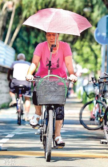 在酷熱天氣警告下,有市民在大埔騎單車也做足防曬措施,打傘乘風而行,以免中暑。(蘇智鑫攝) 在酷熱天氣警告下,有市民在大埔騎單車也做足防曬措施,打傘乘風而行,以免中暑。(蘇智鑫攝)