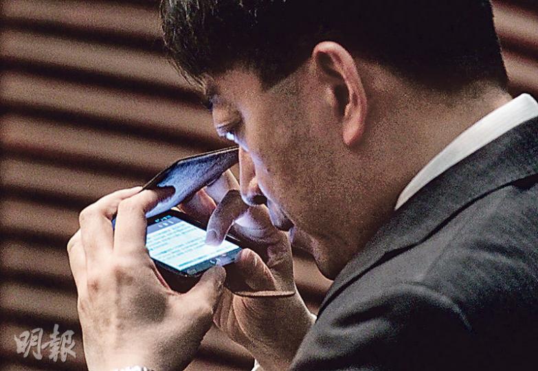 立法會審議政改時,唔少官員同議員睇手機被攝記影到畫面內容,食衛局長高永文噚日就好謹慎,用手機套遮住屏幕,近距離睇手機,但小心壞眼喎。(郭慶輝攝) 立法會審議政改時,唔少官員同議員睇手機被攝記影到畫面內容,食衛局長高永文噚日就好謹慎,用手機套遮住屏幕,近距離睇手機,但小心壞眼喎。(郭慶輝攝)