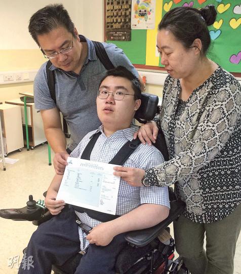 先天患有杜興氏肌肉營養不良症的何卓明(中),需以輪椅代步,寫字亦有困難,但文憑試仍考獲5科14分,他感激身旁的父母每天夜半都幫他轉身以免肌肉疼痛,「真的很感激他們的付出」。(余瑋攝) 先天患有杜興氏肌肉營養不良症的何卓明(中),需以輪椅代步,寫字亦有困難,但文憑試仍考獲5科14分,他感激身旁的父母每天夜半都幫他轉身以免肌肉疼痛,「真的很感激他們的付出」。(余瑋攝)