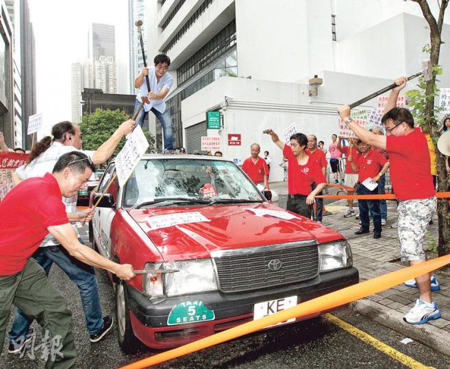30多名的士業界代表昨示威,促當局全面取締白牌車,並以鐵槌打爛的士表達不滿。(李紹昌攝) 30多名的士業界代表昨示威,促當局全面取締白牌車,並以鐵槌打爛的士表達不滿。(李紹昌攝)
