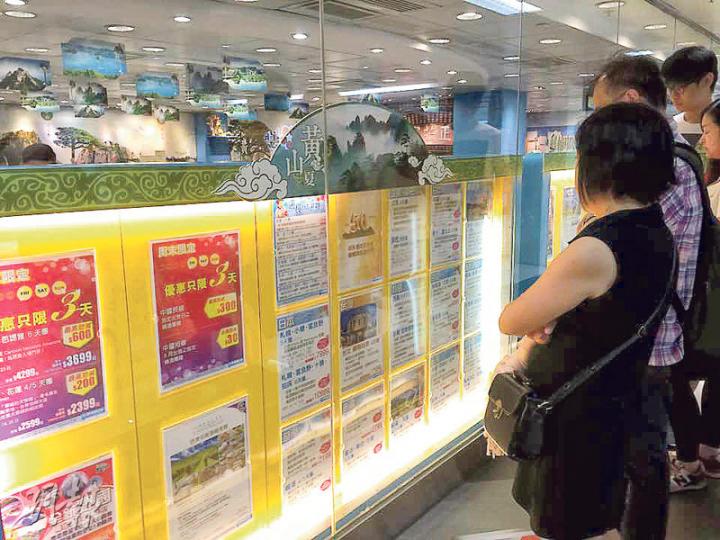 政府昨日取消對韓國的紅色外遊警示,有旅行社推出低至2000多元優惠團,不少市民駐足門外看相關宣傳單張。(沈燕媚攝) 政府昨日取消對韓國的紅色外遊警示,有旅行社推出低至2000多元優惠團,不少市民駐足門外看相關宣傳單張。(沈燕媚攝)