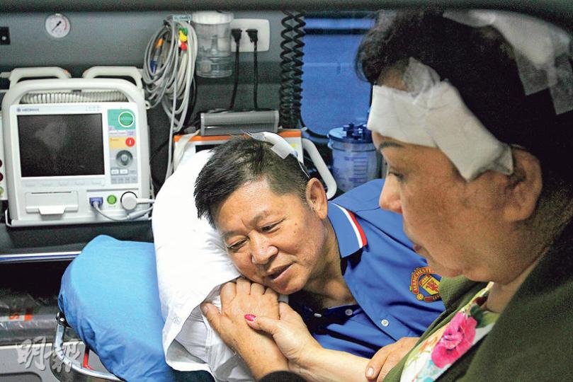 已出院的60歲傷者黃亞娟(右),昨早到醫院會合同樣受傷的62歲丈夫朱日安(左),準備昨午乘飛機回港。她在救護車上陪伴躺在擔架牀上的丈夫,兩人緊握雙手。(林俊源攝) 已出院的60歲傷者黃亞娟(右),昨早到醫院會合同樣受傷的62歲丈夫朱日安(左),準備昨午乘飛機回港。她在救護車上陪伴躺在擔架牀上的丈夫,兩人緊握雙手。(林俊源攝)