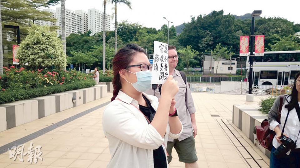 女大學生陳明鳳(戴口罩者)被裁定阻差辦公罪脫後表現興奮, 在庭外以寫有「守護香港」及「路線不同、目標一致」等字句的字牌掩面離開法庭。(張梓鈴攝) 女大學生陳明鳳(戴口罩者)被裁定阻差辦公罪脫後表現興奮, 在庭外以寫有「守護香港」及「路線不同、目標一致」等字句的字牌掩面離開法庭。(張梓鈴攝)