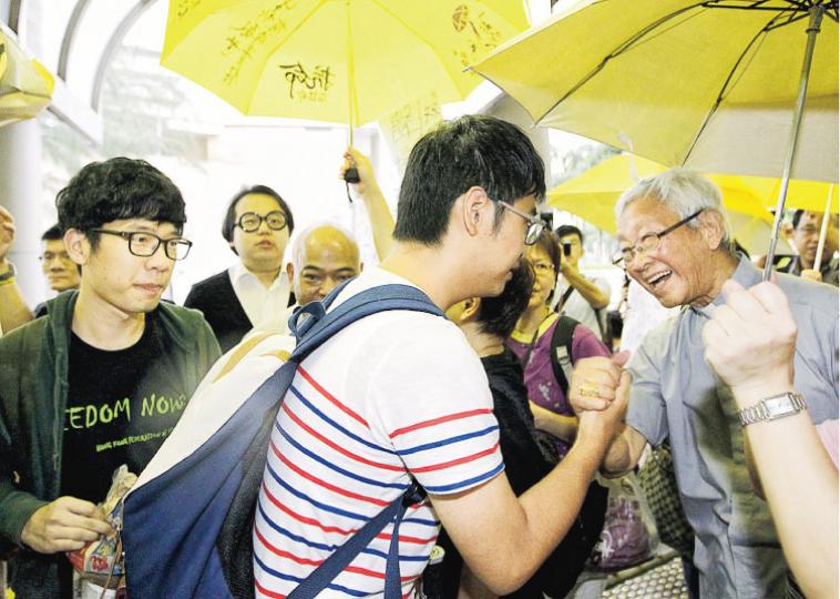 天主教香港教區榮休主教陳日君樞機(右一)昨早到東區裁判法院,聲援被檢控的學聯前秘書長周永康(白衣者)等人,其間陳與周互相握手鼓勵。(郭慶輝攝) 天主教香港教區榮休主教陳日君樞機(右一)昨早到東區裁判法院,聲援被檢控的學聯前秘書長周永康(白衣者)等人,其間陳與周互相握手鼓勵。(郭慶輝攝)