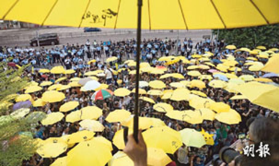 昨日不少市民重返金鐘,出席民陣與民間團體舉行的佔領運動一周年集會;其間市民響應大會呼籲,於傍晚5時58分、即一年前警方發射第一枚催淚彈驅散市民的時間,舉起黃傘默站15分鐘。同一時間,身穿藍色制服的警員,在圖中遠處築起重重人牆及鐵馬陣,防止有人衝出夏愨道。警方稱,昨有1100人在政總一帶參與活動,當中包括180名反佔中者。(鍾林枝攝)民陣聯同民間團體昨在政府總部對開行人路舉行「全民反政治打壓運動」集會,紀念佔領運動一周年。大會在傍晚5時58分、即去年警方發射第一枚催淚彈驅散市民的時間,帶領市民舉起 昨日不少市民重返金鐘,出席民陣與民間團體舉行的佔領運動一周年集會;其間市民響應大會呼籲,於傍晚5時58分、即一年前警方發射第一枚催淚彈驅散市民的時間,舉起黃傘默站15分鐘。同一時間,身穿藍色制服的警員,在圖中遠處築起重重人牆及鐵馬陣,防止有人衝出夏愨道。警方稱,昨有1100人在政總一帶參與活動,當中包括180名反佔中者。(鍾林枝攝)民陣聯同民間團體昨在政府總部對開行人路舉行「全民反政治打壓運動」集會,紀念佔領運動一周年。大會在傍晚5時58分、即去年警方發射第一枚催淚彈驅散市民的時間,帶領市民舉起