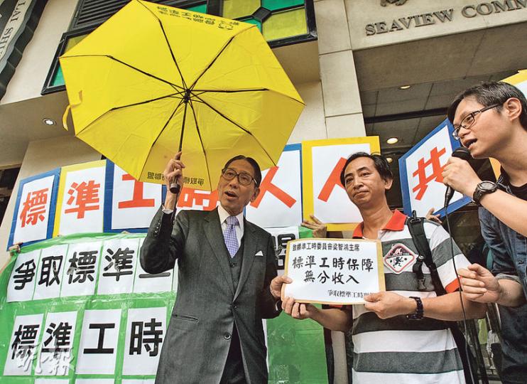 爭取標準工時聯盟昨早向標時會請願,要求盡快落實標準工時,及抗議以工資水平劃界。標時會主席梁智鴻(左)親自接請願信及印有「標準工時唔少得」字樣的黃傘。(李紹昌攝) 爭取標準工時聯盟昨早向標時會請願,要求盡快落實標準工時,及抗議以工資水平劃界。標時會主席梁智鴻(左)親自接請願信及印有「標準工時唔少得」字樣的黃傘。(李紹昌攝)