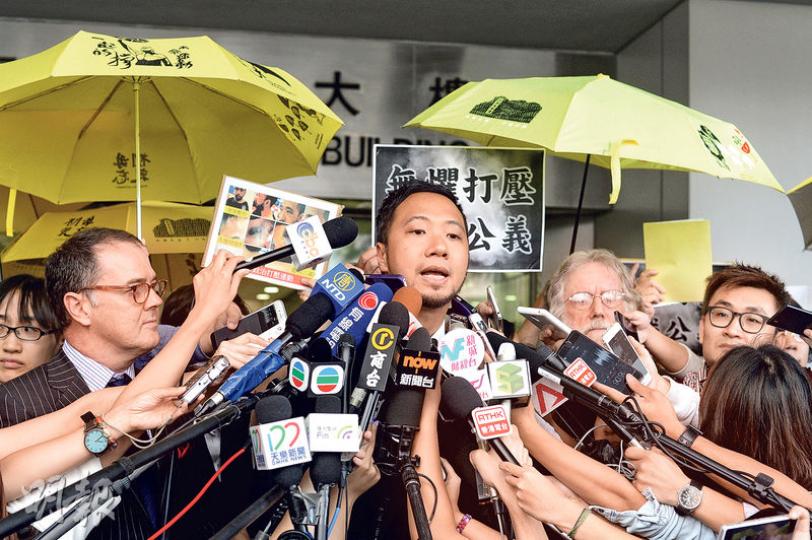 曾健超被控:1項襲警及4項拒捕罪 - 疑被7名警員毆打的曾健超(中)昨在庭外說感謝香港市民支持,並以「支持公義、勇敢面對、政治打壓、不屈不撓」16個字表達感受,其間約有30名支持者撐黃傘及大叫「加油」。他在另案被控1項襲警及4項拒捕罪。右方外籍人士為代表曾健超的大律師麥嘉汶。(鍾林枝攝) 曾健超被控:1項襲警及4項拒捕罪 - 疑被7名警員毆打的曾健超(中)昨在庭外說感謝香港市民支持,並以「支持公義、勇敢面對、政治打壓、不屈不撓」16個字表達感受,其間約有30名支持者撐黃傘及大叫「加油」。他在另案被控1項襲警及4項拒捕罪。右方外籍人士為代表曾健超的大律師麥嘉汶。(鍾林枝攝)