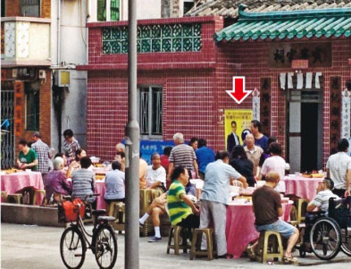 粉嶺樓村昨日黃昏於祠堂外舉辦盆菜宴,同一地點豎有粉嶺市區選候選人彭振聲的競選宣傳「易拉架」(箭嘴示)。(梁智康攝) 粉嶺樓村昨日黃昏於祠堂外舉辦盆菜宴,同一地點豎有粉嶺市區選候選人彭振聲的競選宣傳「易拉架」(箭嘴示)。(梁智康攝)