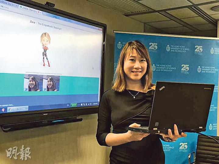 科大教授馮雁研發出其背後屏幕中嘅「超級少女Zara」，Zara可透過視像鏡頭判斷用家種族同語言，但暫只限以英文同普通話溝通。（梁煥敏攝）