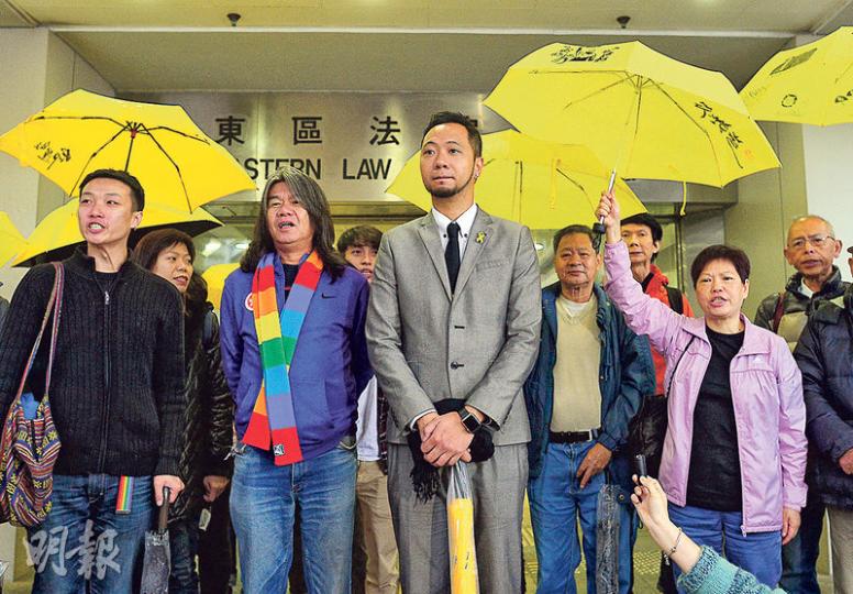 被告曾健超(前左三)昨離庭時仍下着雨,他穿上灰色西裝,衣領上繫上黃絲帶心口針,在立法會議員梁國雄(前左二)及一眾撐起黃傘的支持者陪同下到庭,他們散庭後在庭外高叫「和平示威無罪,公民抗命無罪」口號。(鄧宗弘攝) 被告曾健超(前左三)昨離庭時仍下着雨,他穿上灰色西裝,衣領上繫上黃絲帶心口針,在立法會議員梁國雄(前左二)及一眾撐起黃傘的支持者陪同下到庭,他們散庭後在庭外高叫「和平示威無罪,公民抗命無罪」口號。(鄧宗弘攝)