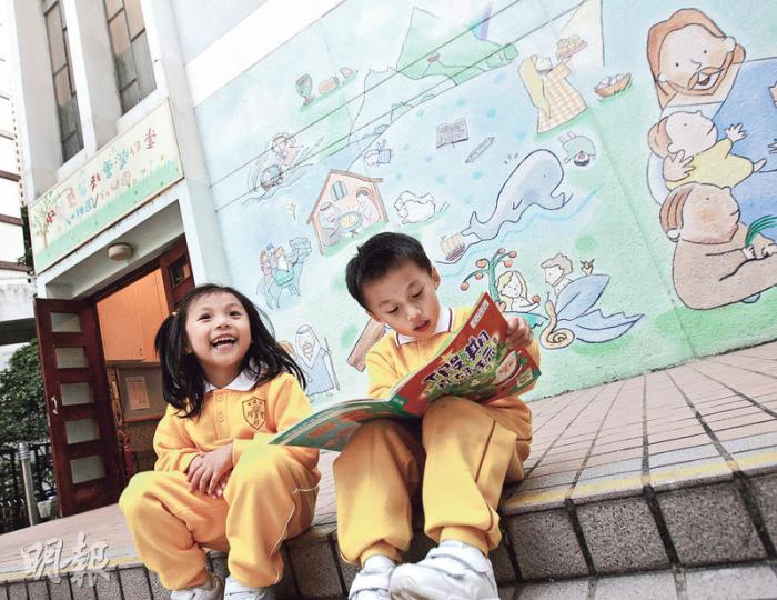 中華基督教會灣仔堂幼稚園在學校網站中列明有小一銜接課程，包括中英數及常識，校長表示課程主要從形式上模擬小學，但教學內容是幼園程度，如中英文都是通過故事形式學習，不會要求學生拼寫詞語。圖為兩名學生在該幼稚園門外看圖書。（李紹昌攝）