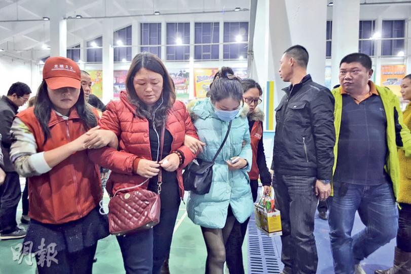 失蹤的福建民工林彬在肇事的泥頭堆填區工作，至今杳無音信；其母親（左二）及妻子（左三）前晚由福建趕往災場尋人，但被趕走，無奈要到安置點等消息。（蘇智鑫攝）逃過一劫的民工帶同年幼孩子到安置點暫住，當局派出義工（紅衣者）協助災民。（蘇智鑫攝）