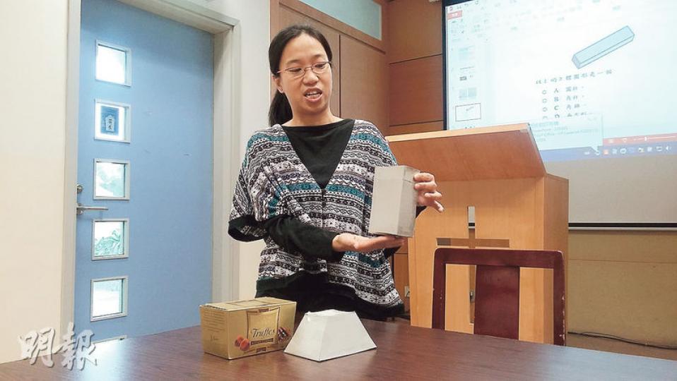數學科教師陳詩韻舉例,有些朱古力盒(枱上左邊)屬不規則圖形,不在教學範圍,卻屬基本能力,會出現在TSA試題,故她會自製教具解釋角柱體與不規則立體圖形的區別。(田青青攝) 數學科教師陳詩韻舉例,有些朱古力盒(枱上左邊)屬不規則圖形,不在教學範圍,卻屬基本能力,會出現在TSA試題,故她會自製教具解釋角柱體與不規則立體圖形的區別。(田青青攝)